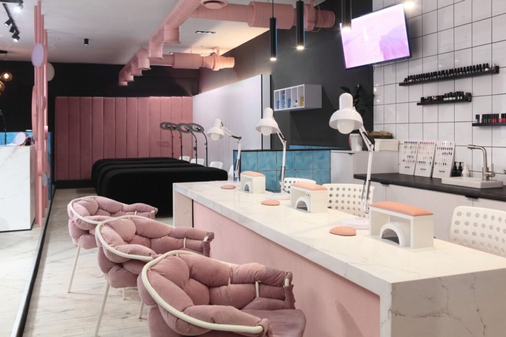 Sala com cadeiras e luminárias da cor rosa e bancada branca 