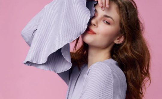 Mulher usando maquiagem rosa e posando para foto em um fundo rosa