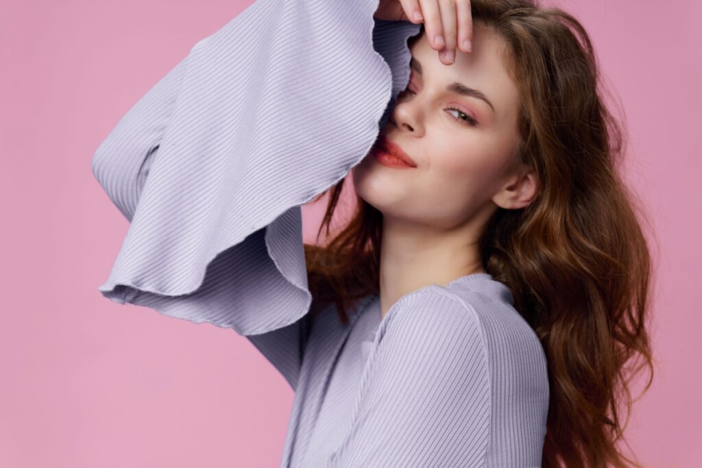 Mulher usando maquiagem rosa e posando para foto em um fundo rosa