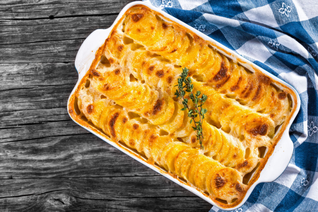 Batata gratinada em travessa com pano azul e branco ao lado