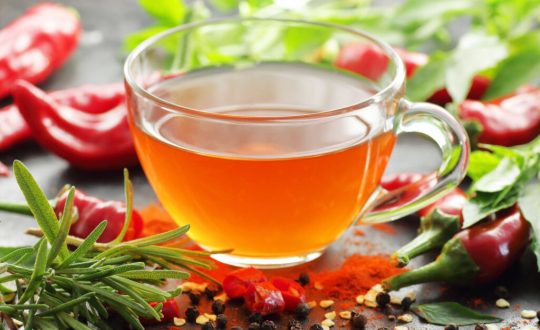 Chá de pimenta com ervas em xícara de vidro com pimentas e ervas ao redor