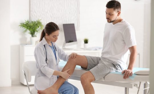 Médica examinando o joelho de um homem
