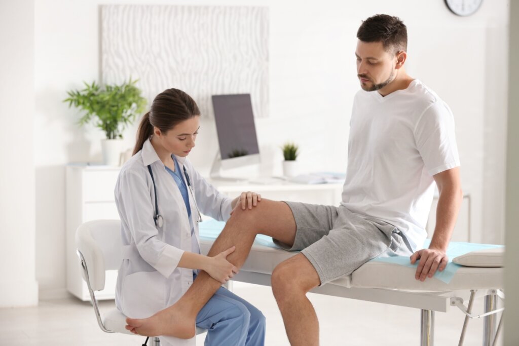 Médica examinando o joelho de um homem