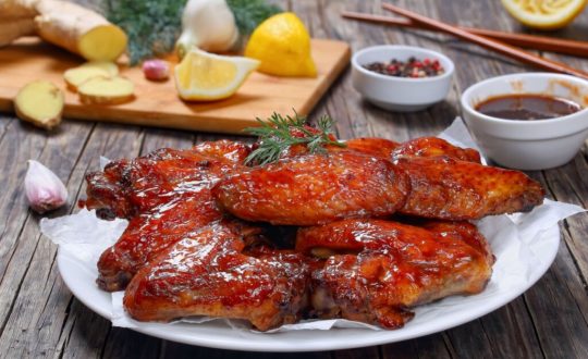 Frango assado ao molho caramelizado de mel, alho e gengibre, servido com ervas frescas sobre papel-manteiga