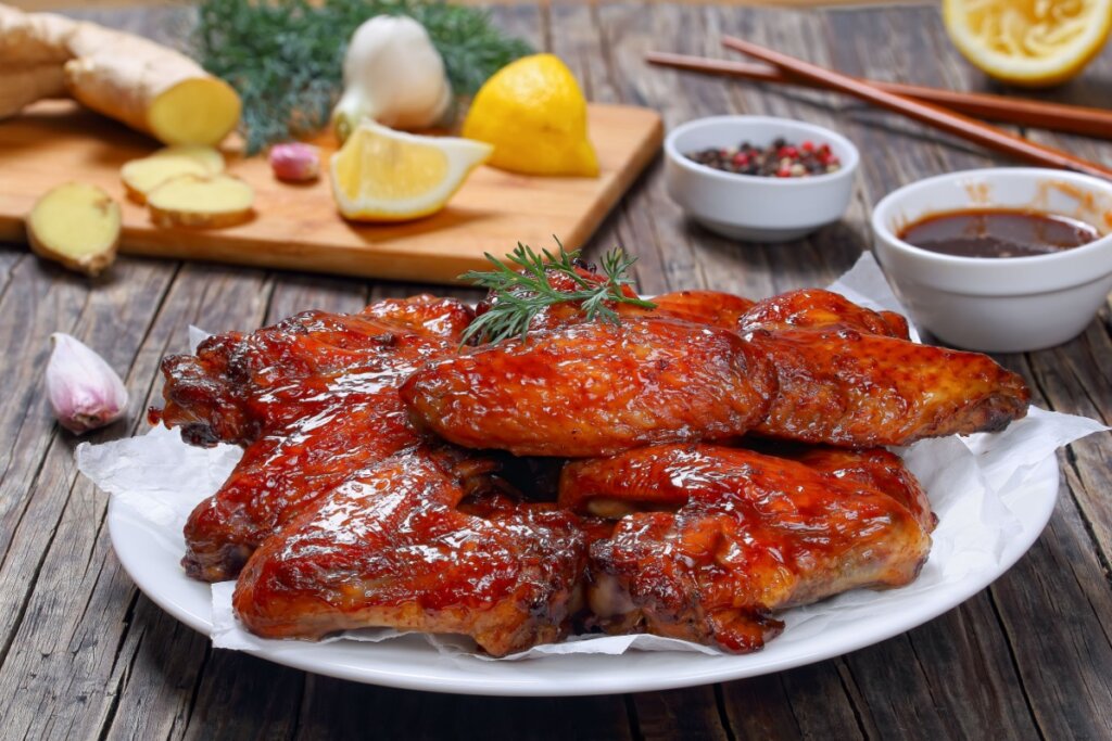Frango assado ao molho caramelizado de mel, alho e gengibre, servido com ervas frescas sobre papel-manteiga