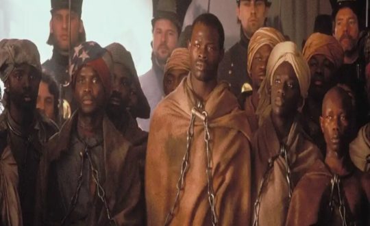 imagem com homens negros com roupas marrom e acorrentados pelo pescoço