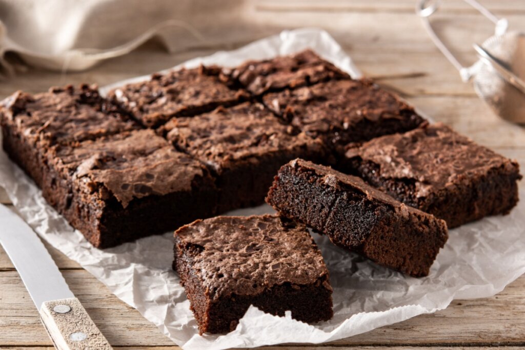 Brownie servido em cima de papel manteiga em cima de mesa de madeira