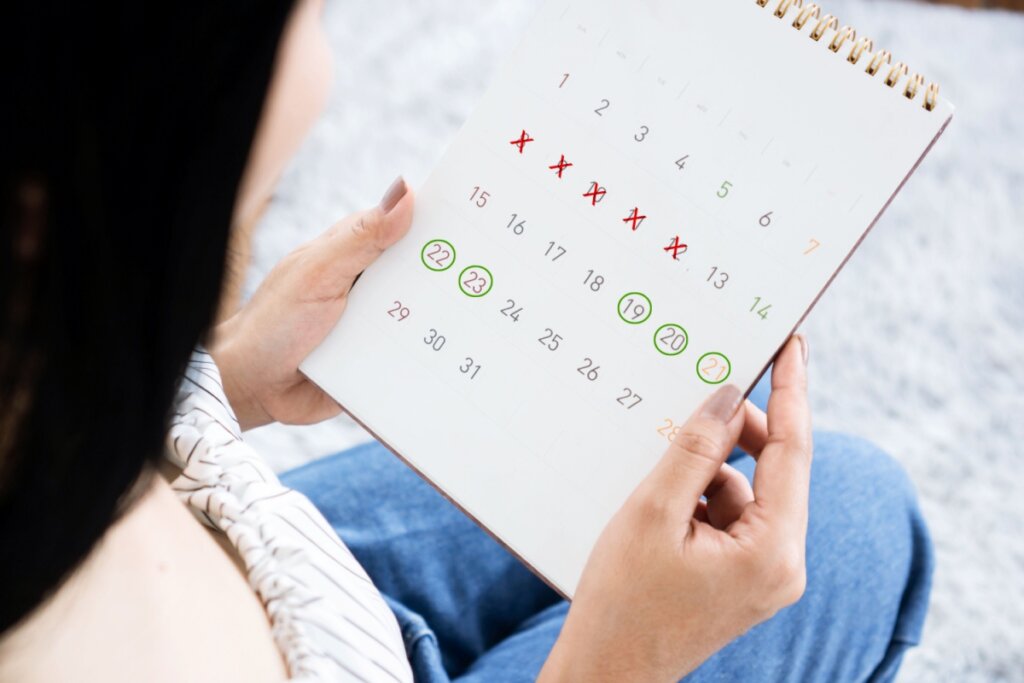 Calendário com "x" e círculos verdes marcando o ciclo menstrual 