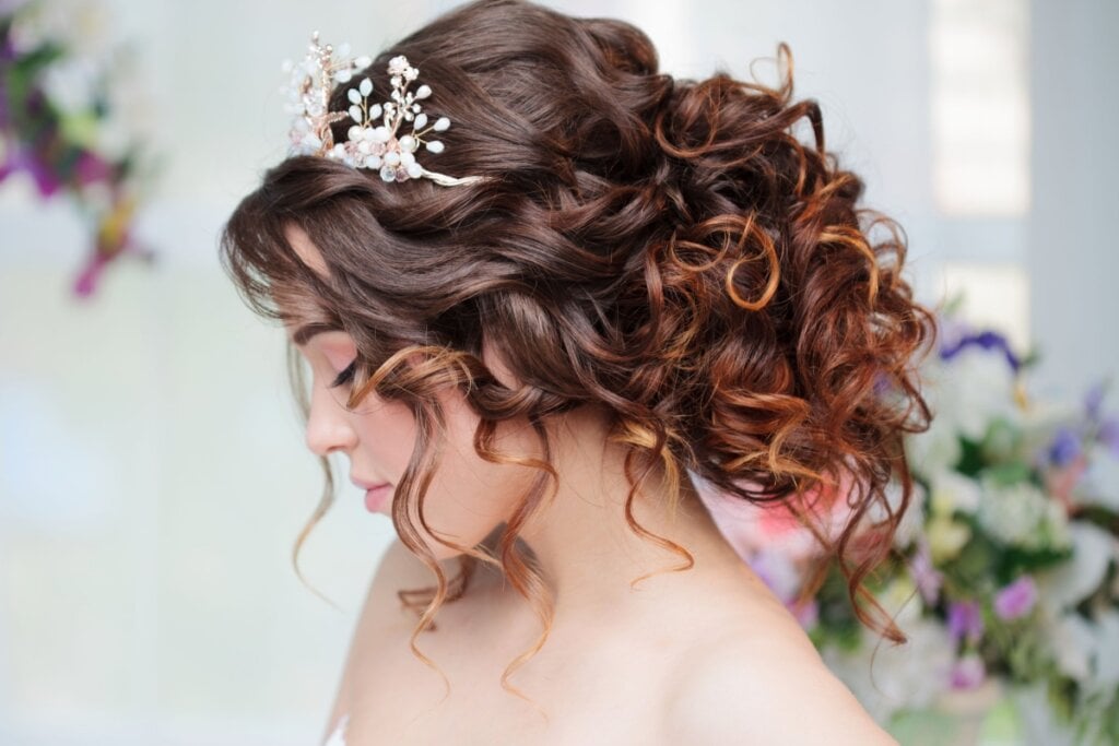 Mulher vestida de noiva com o cabelo com penteado preso em coque com fios soltos e cacheados 