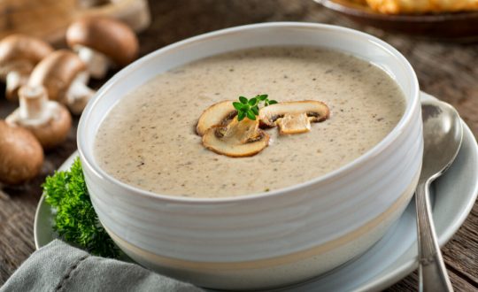 Creme de cogumelo em recipiente branco com colher ao lado