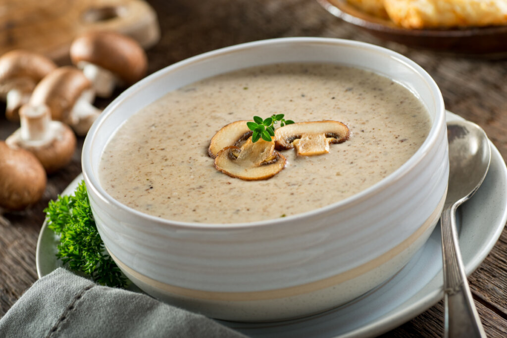 Creme de cogumelo em recipiente branco com colher ao lado