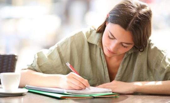estudante escrevendo em um caderno