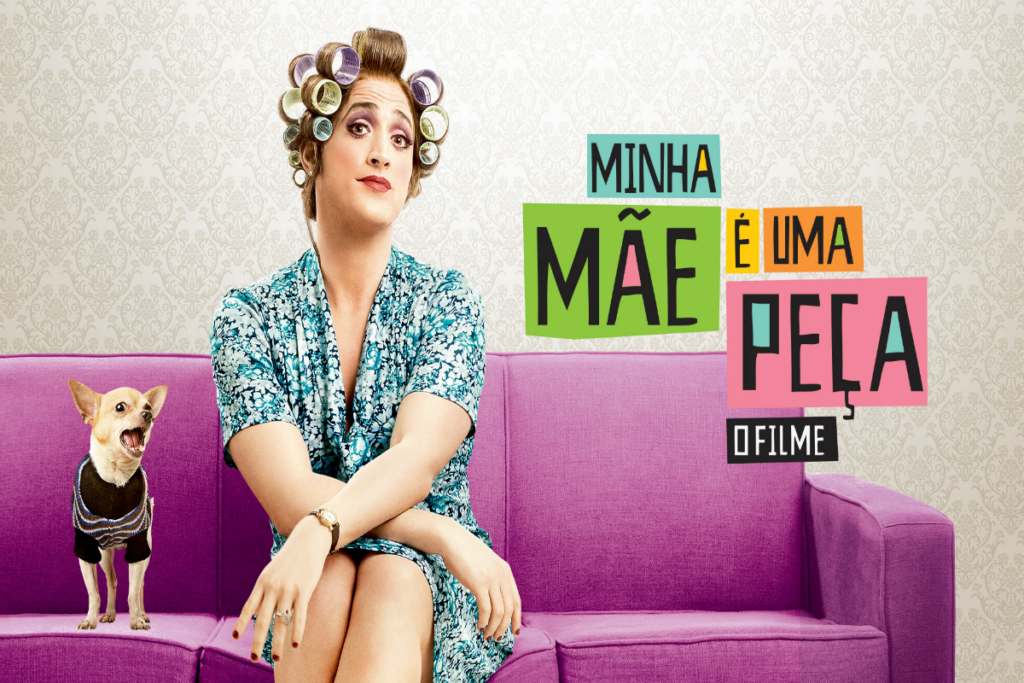 Mulher com bobes no cabelo, e usando um vestido estampado, sentada ao lado de um cachorro com roupa preta sentada em um sofá roxo e com o nome do filme ao lado na imagem