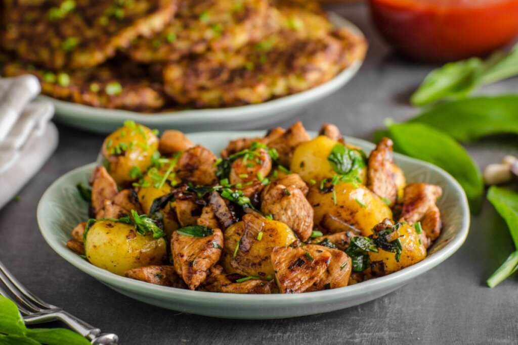 Prato branco com frango grelhado com batata e folhas de taioba 