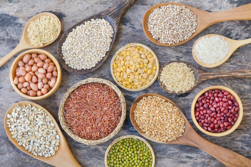 Diversas cumbucas com grãos como arroz, milho, feijão em cima de mesa de pedra