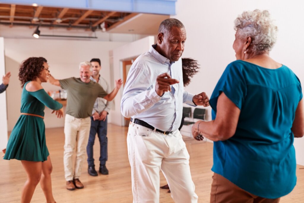 cinco pessoas felizes e dançando em uma ambiente fechado