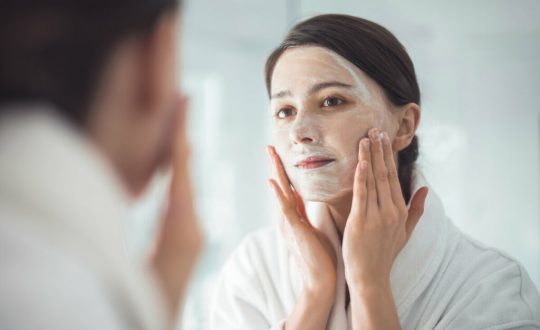 Mulher com o rosto ensaboado se olhando no espelho