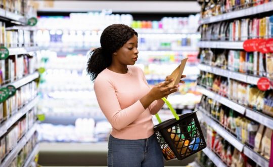Mulher lendo rótulo de um produto no mercado