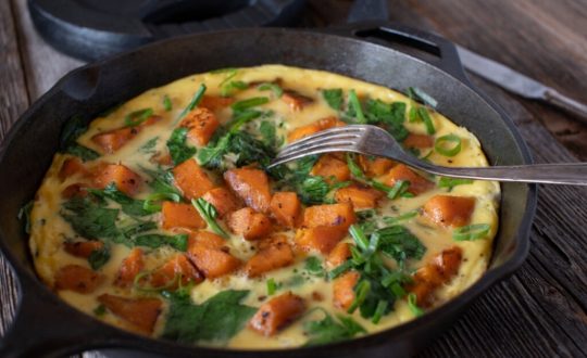 Frigideira preta com omelete de batata-doce com espinafre