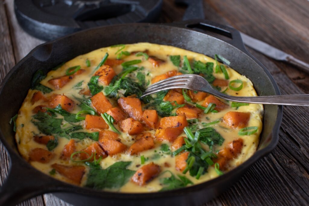 Frigideira preta com omelete de batata-doce com espinafre 