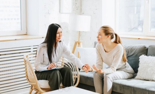 Mulher sentada em sofá conversando com psicóloga