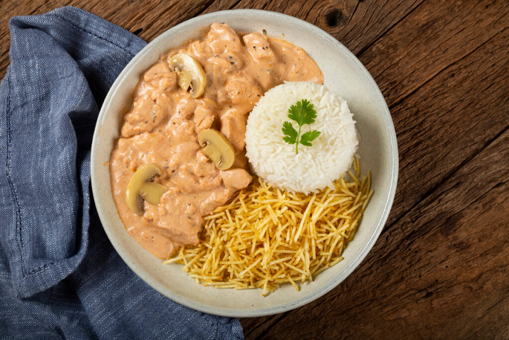 Prato branco com estrogonofe de frango, arroz e batata-palha