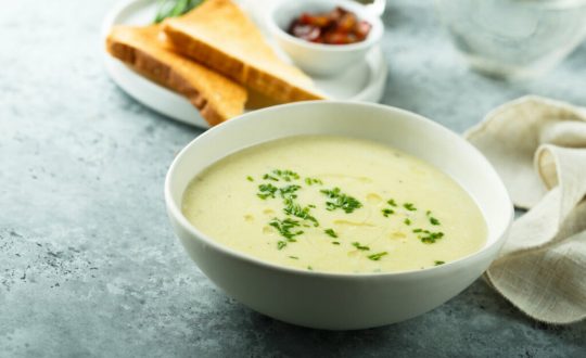 Recipiente branco com sopa de alho polvilhada com salsinha