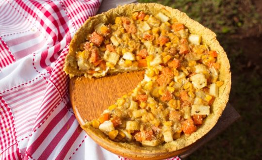 Torta rústica de palmito com legumes em mesa de madeira com pano  branco e vermelho