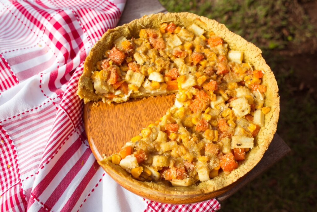 Torta rústica de palmito com legumes em mesa de madeira com pano  branco e vermelho